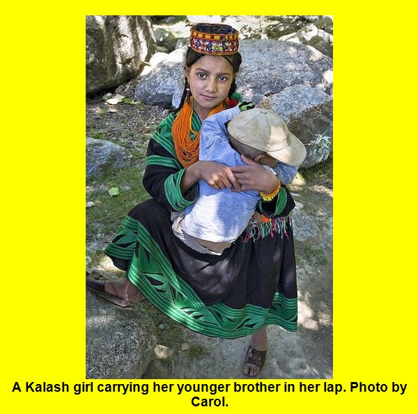 Kalash Photos, Images; A Kalash girl carrying her younger brother - Kalash Valleys Pictures, Chitral Kalasha Pics, Images: A Kalash girl carrying her younger brother in her lap, Rumbur Valley - Photos Kalash Valleys of Chitral