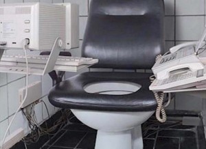 Phone, fax and computer fitted near the commode seat in a toilet (Restroom): Write a Creative Caption to Practice Caption-Writing for Contests