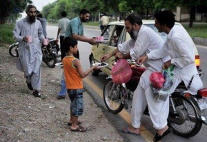 Ramzan (Ramadan): A child with his father offering dates to passengers for breaking the fast (sawm, roza) at iftar