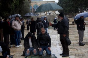 Namaz Pictures - Two persons are offering Namaz in the rain, an old man is trying to protect them with an umbrella - Namaz (Salat) Photos