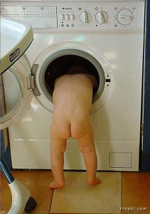 Funny photos of baby; A naked baby Searching for clothes in washing machine